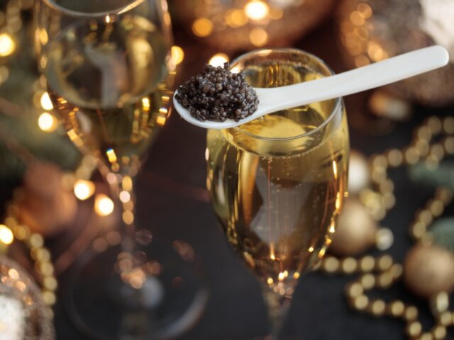A mother-of-pearl spoon of caviar on a Champagne flute